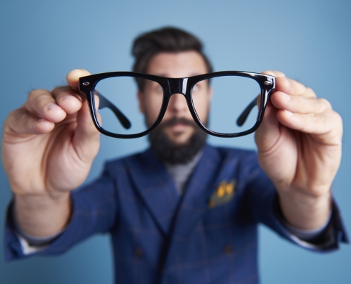 Man holding eyeglasses in front his face